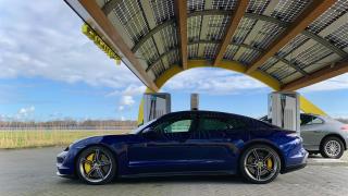 A photo of a blue Porsche Taycan Turbo S charging at a FastNed charging station.